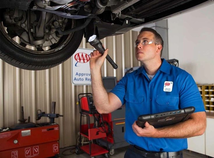 Male technician shining flashlight during vehicle inspection